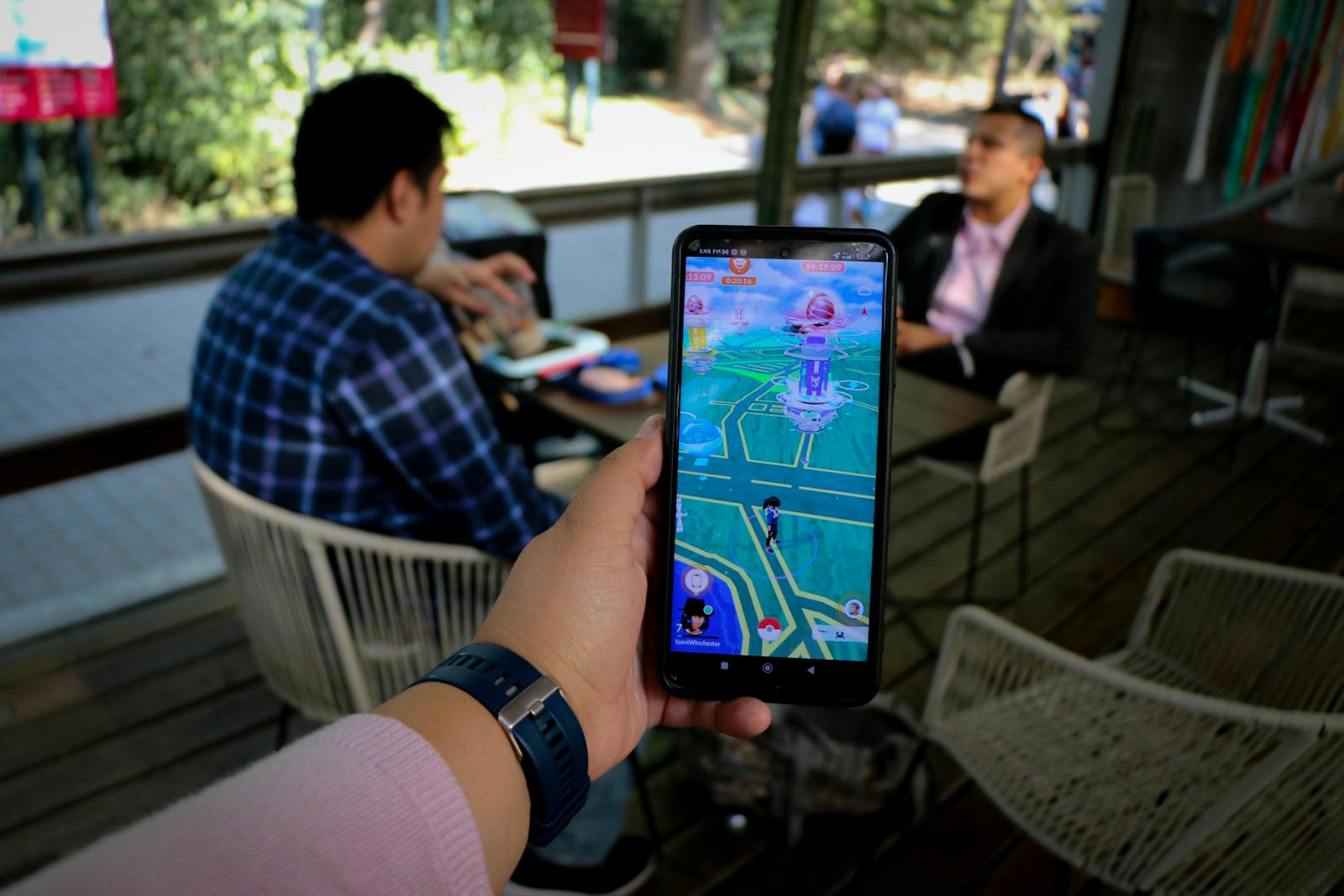 Mobile esports players coordinating around smartphones in a bright lounge